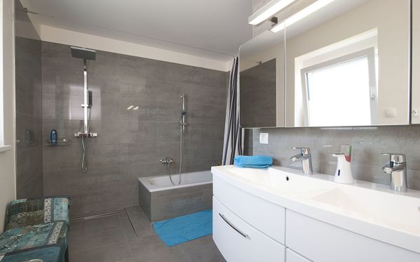 Modernes Badezimmer mit grauen Fliesen und Duschbadewanne