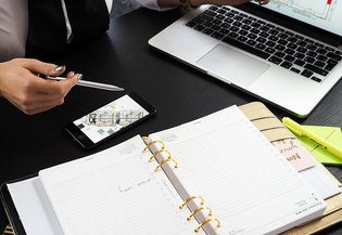 desk with mobile, laptop and notebook