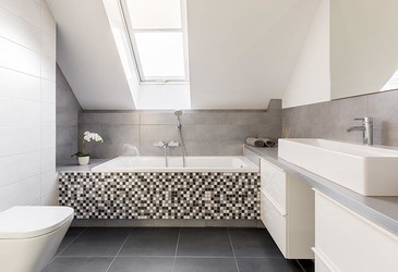 Lichtdurchflutetes Badezimmer mit hellen Fliesen und schrägem Dachfenster