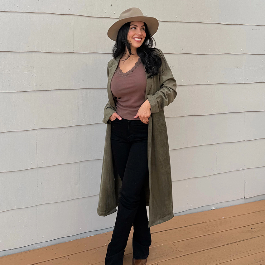 Woman takes a mirror selfie in red pants, black top, and white jacket.