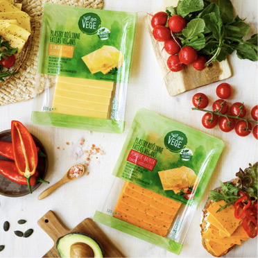 plastry roślinne Go Vege - alternatywa dla sera ż&oacute;łtego, wok&oacute;ł gałązki świeżych pomidork&oacute;w koktajlowych, rzodkiewka, awokado, papryka i rozsypane ziarenka soli