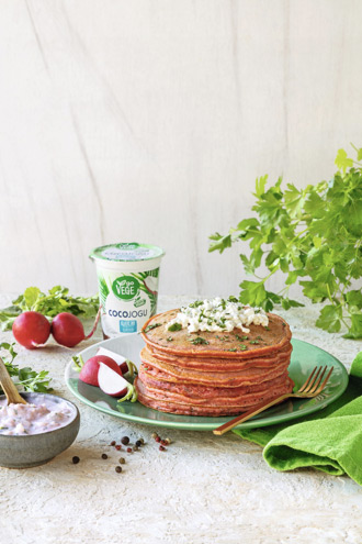 pomarańczowe smoothies w pojemnej, wysokiej szklance, obok kubeczek COCOJOGU produkt wegański o charakterze jogurtu Go Vege. Wok&oacute;ł świeże maliny i poł&oacute;wki cytrus&oacute;w