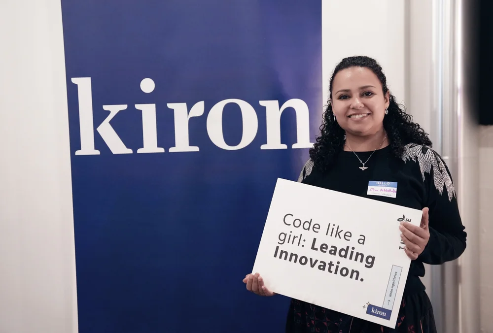 Dina holding up a sign that says "Coding like a girl: Leading innovation"