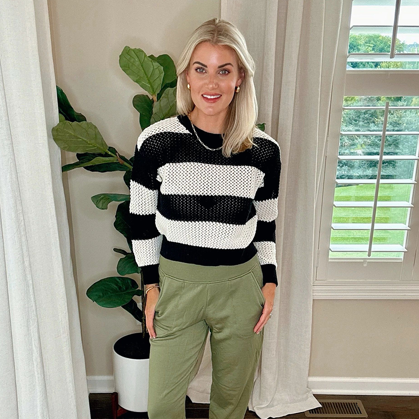 Woman wearing a pink plaid blazer, gray T-shirt, and black jeans.