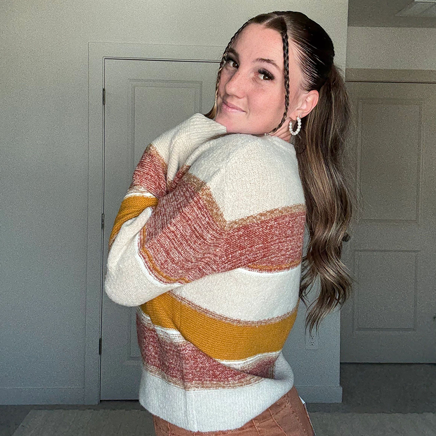 Woman takes a mirror selfie in a houndstooth blazer and ripped jeans.