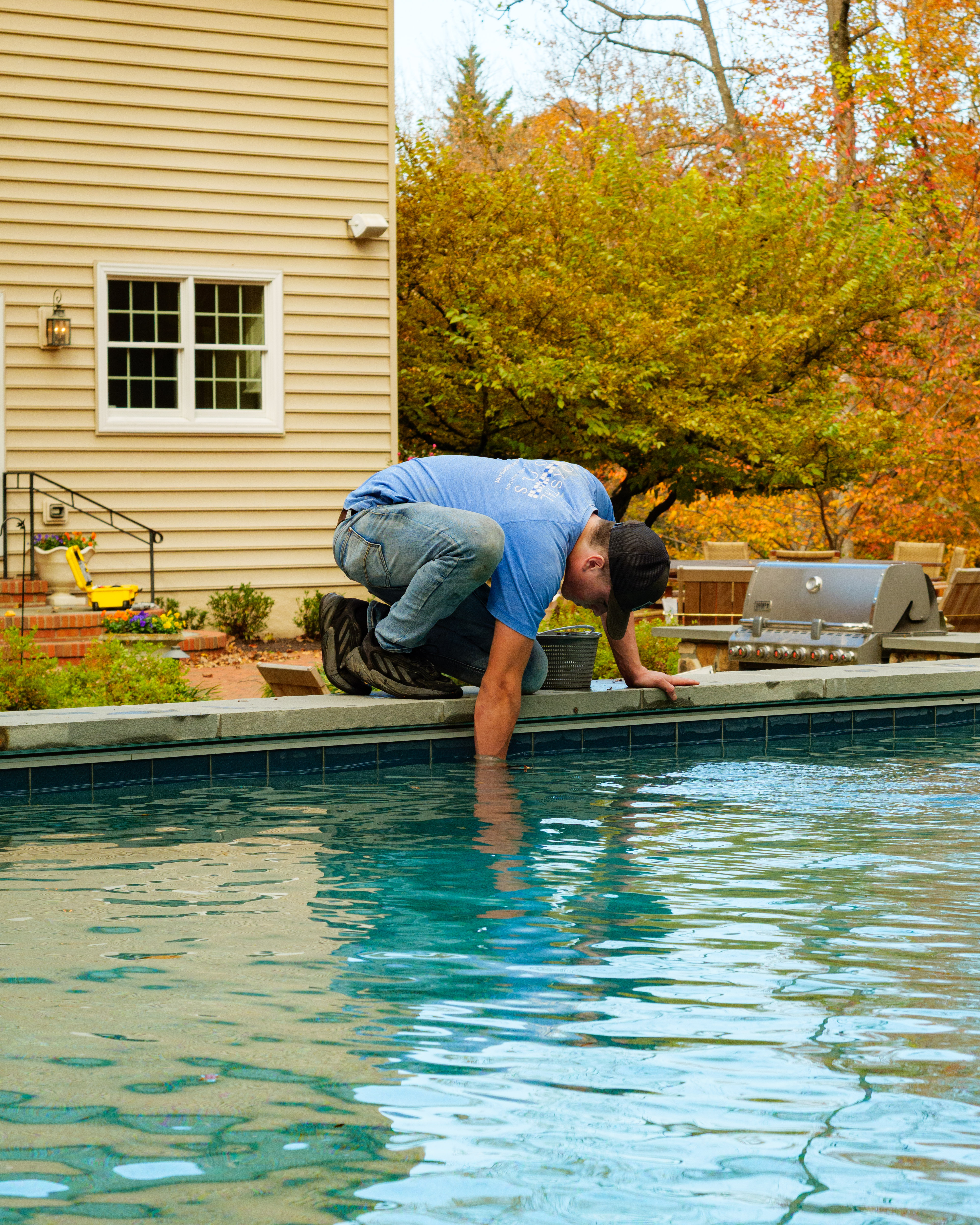 Professional pool closing service Coastal Pools technician servicing an inground pool