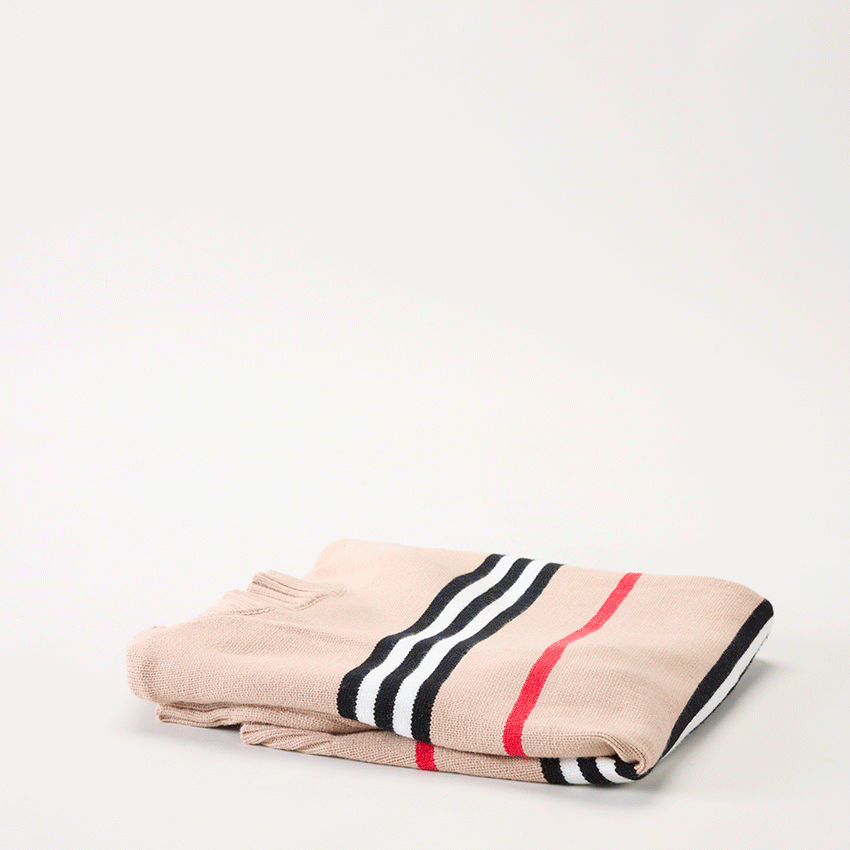 Folded beige knit sweater with black, white, and red stripes.