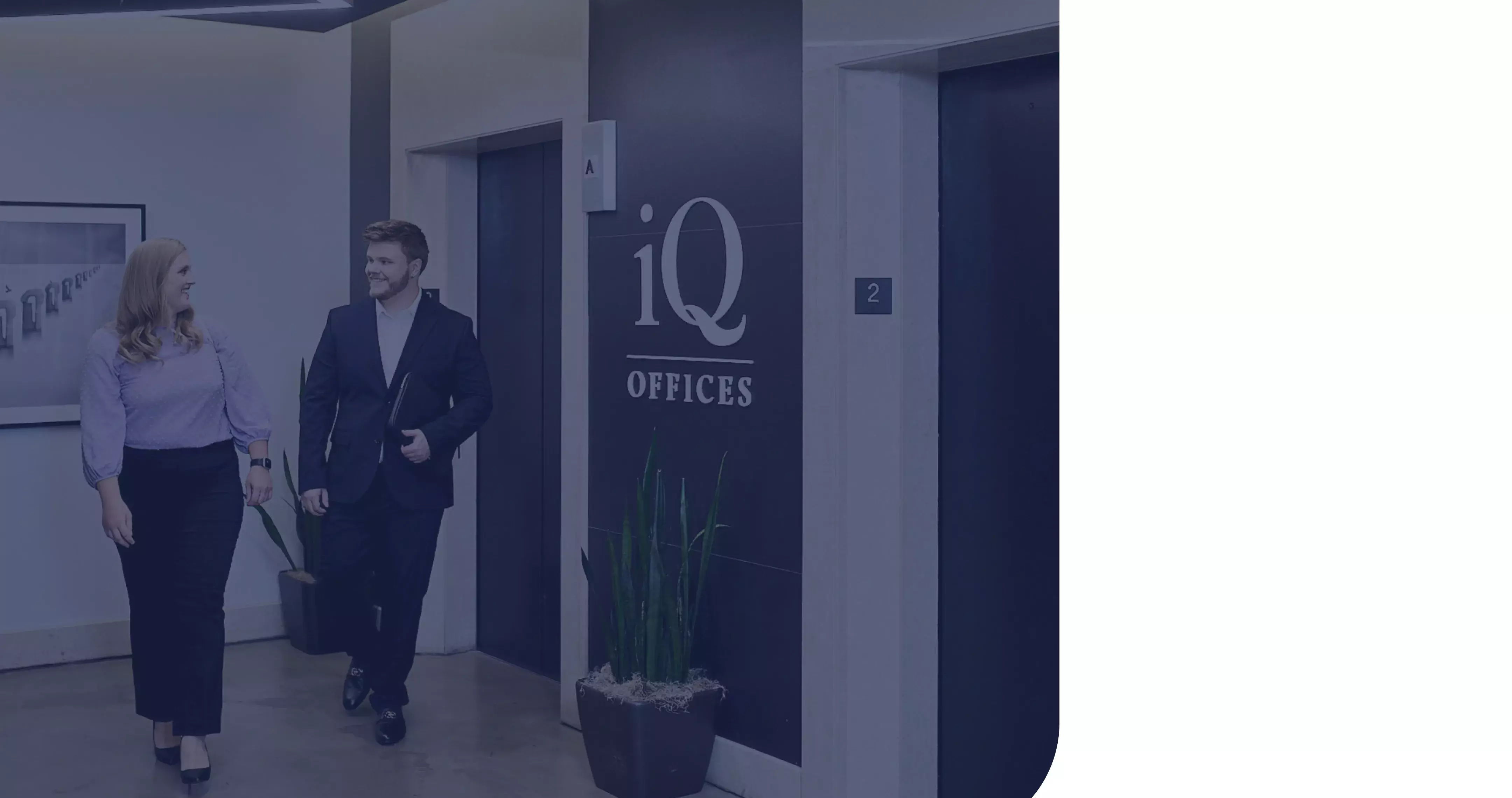 A darkened image of two people getting off an elevator and walking into iQ Offices
