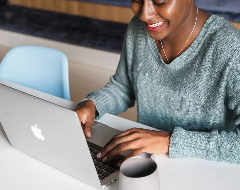 A PoC working on a laptop smiling