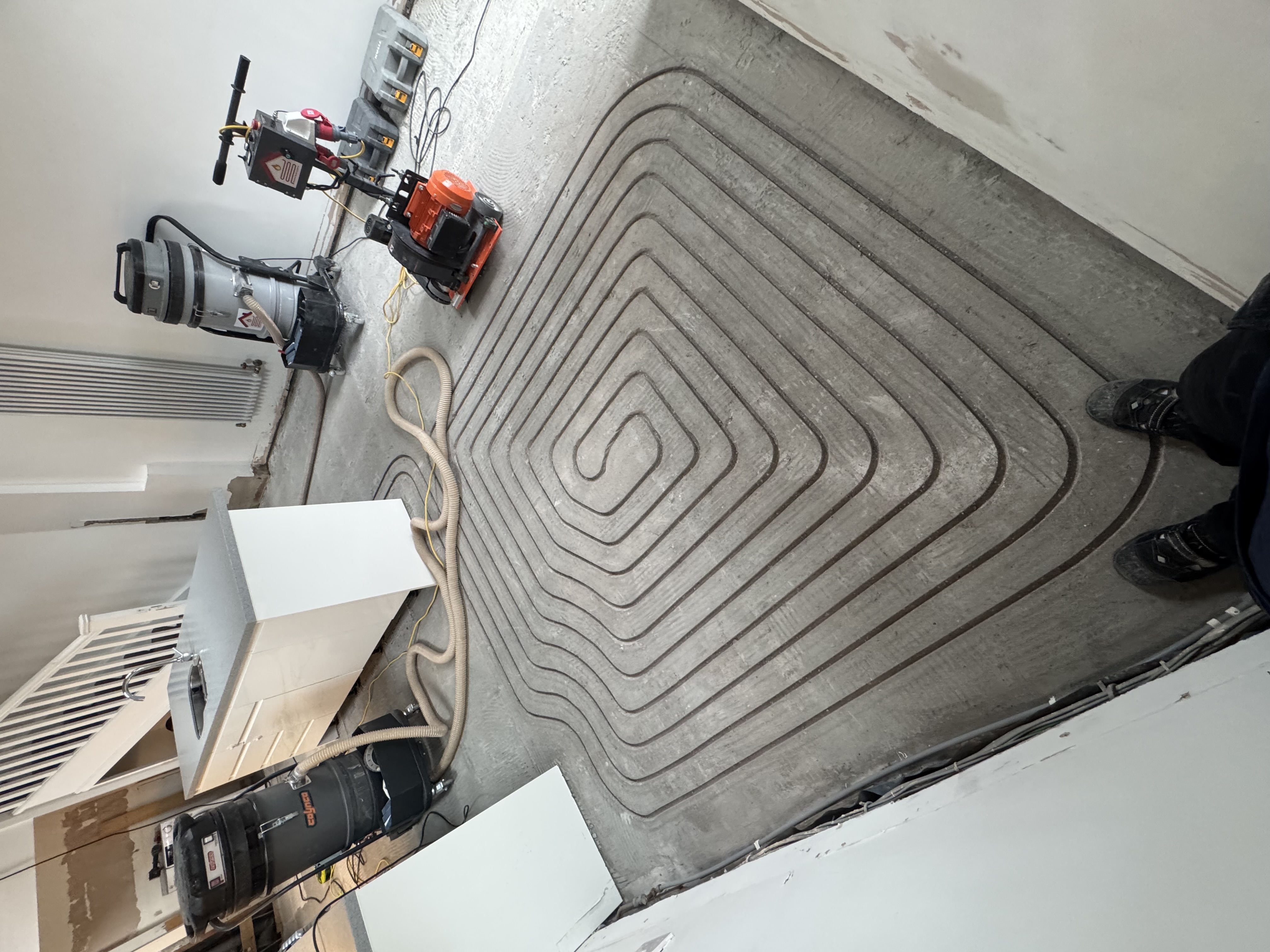 Channels milled into a concrete floor ready for underfloor heating pipes