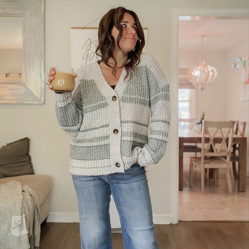 Woman wearing a pink plaid blazer, gray T-shirt, and black jeans.