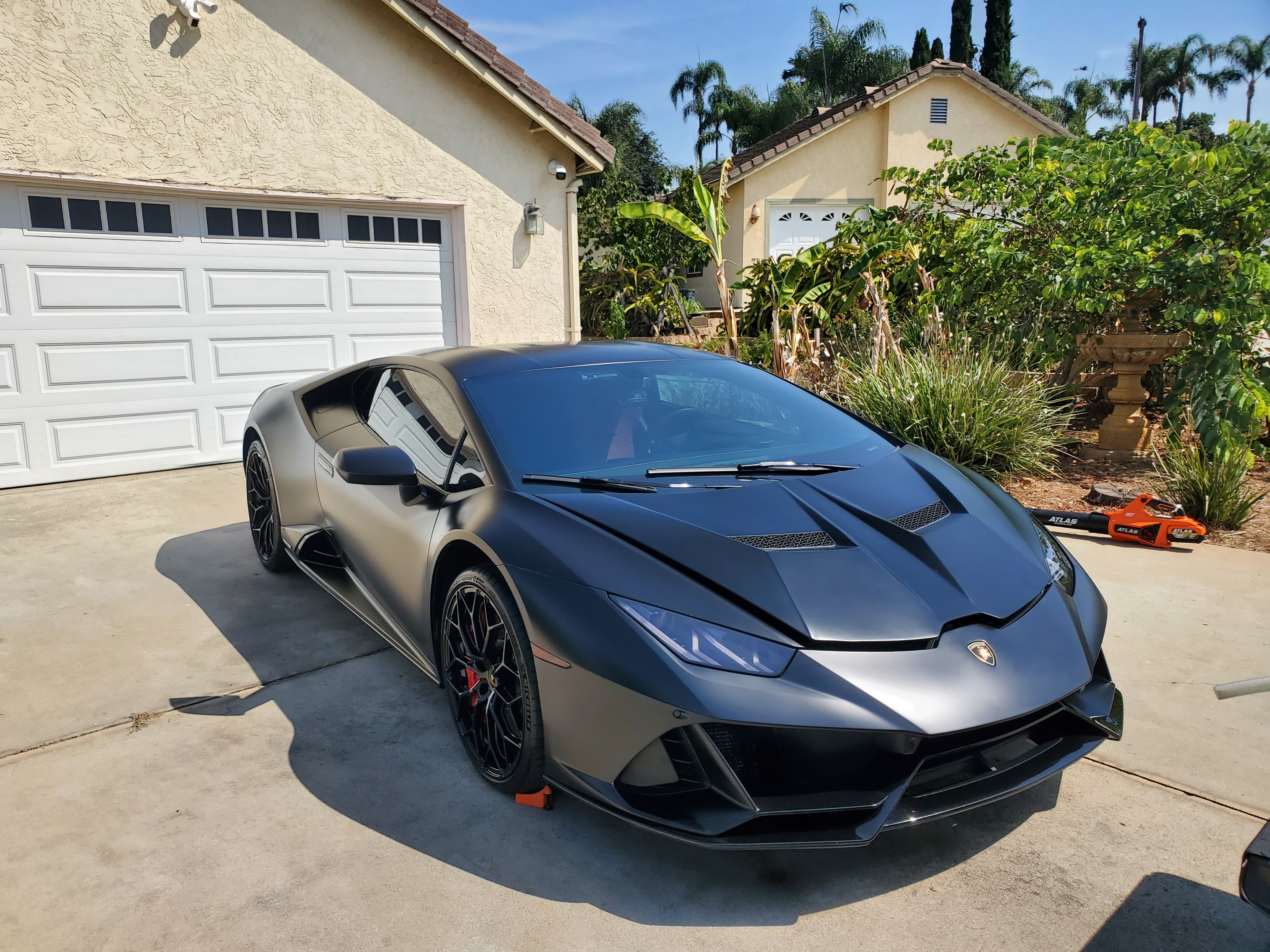 Detailer washing a red sports car in a garage