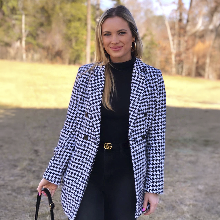 Woman wearing a black-and-white houndstooth blazer over an all-black outfit.