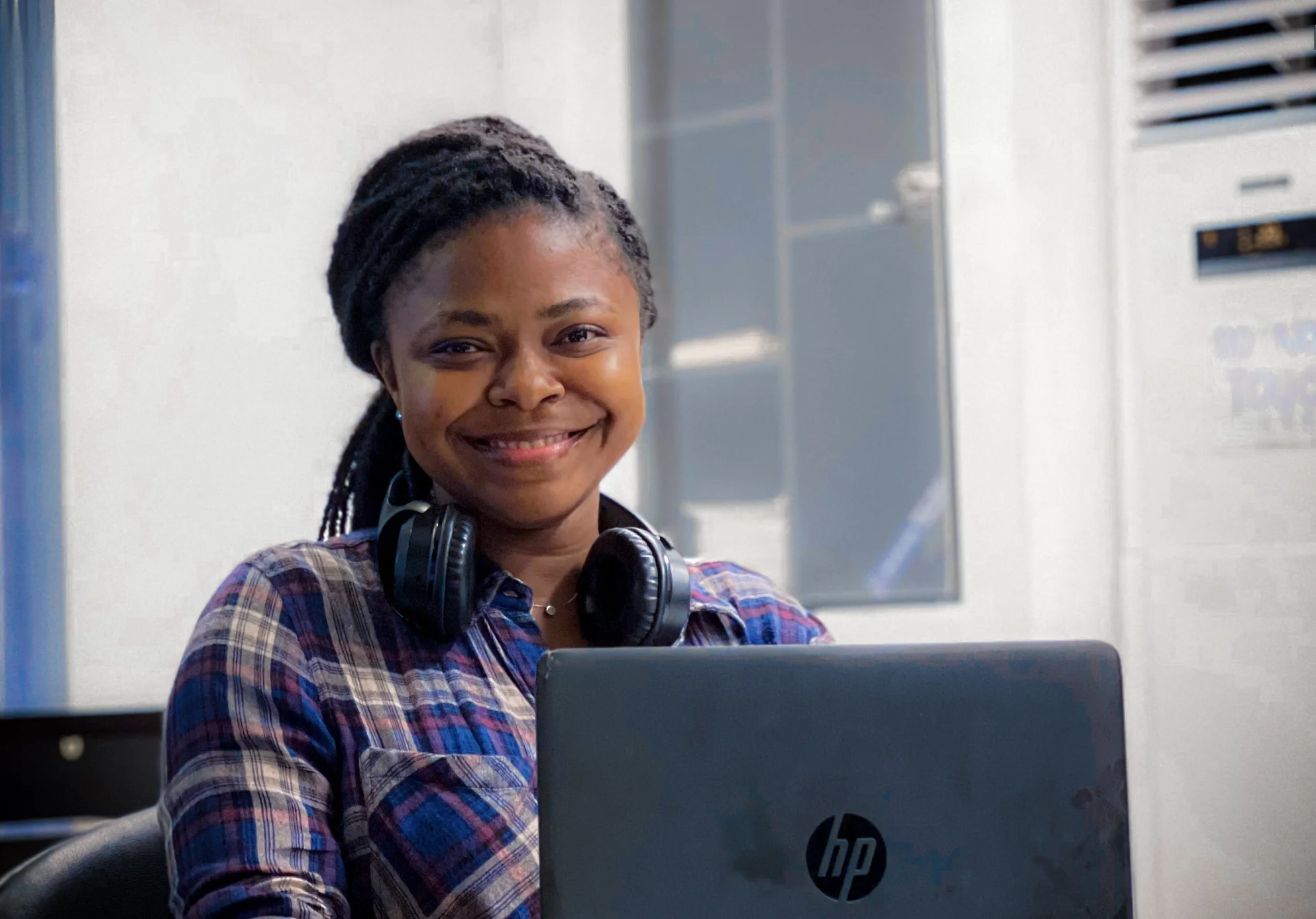 A female PoC sitting in front of a laptop smiling
