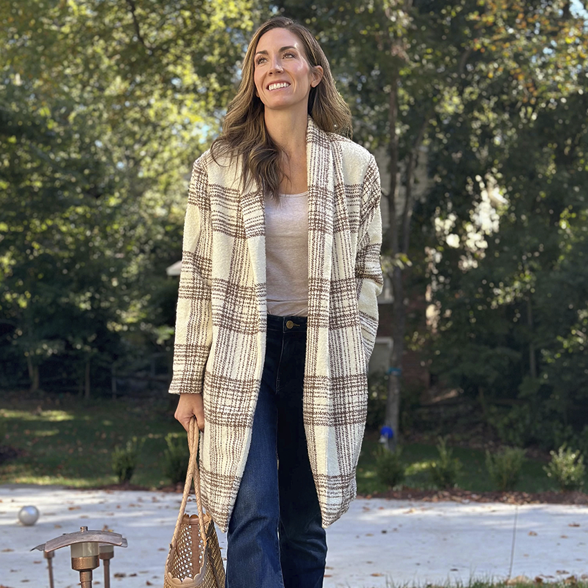 Woman takes a mirror selfie in a houndstooth blazer and ripped jeans.