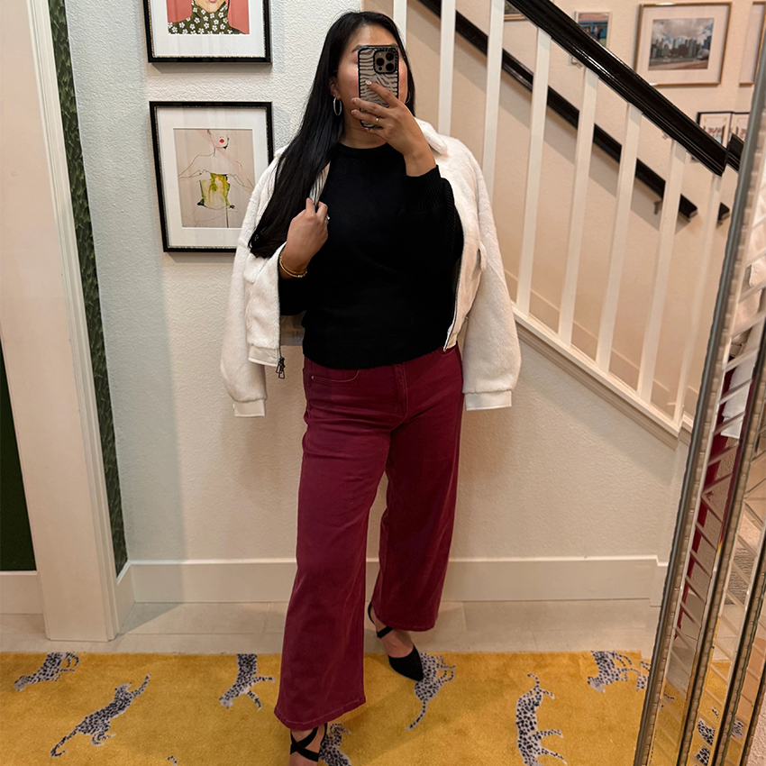 Woman wearing a pink plaid blazer, gray T-shirt, and black jeans.