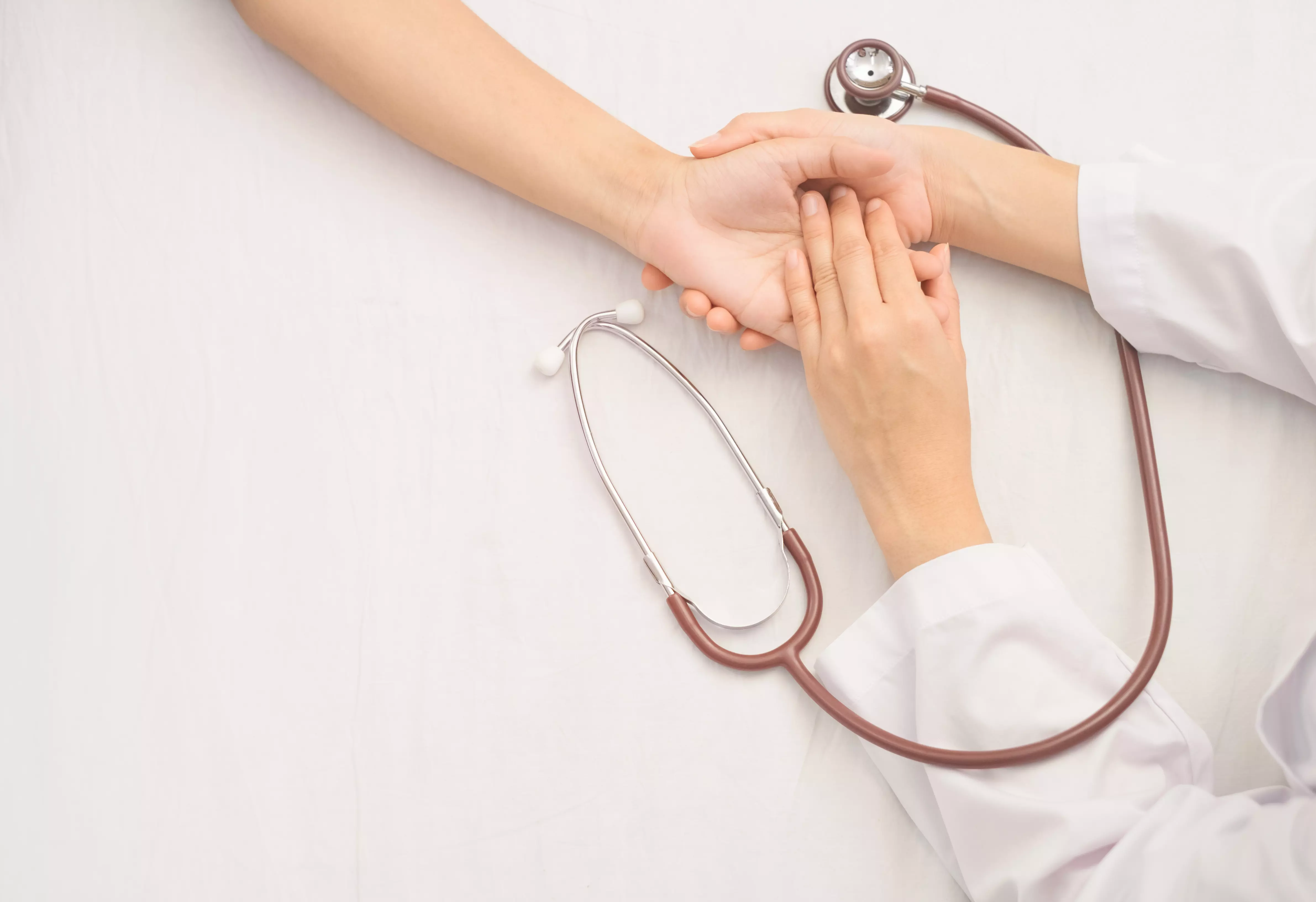 Imagem de um médico segurando a mão de uma paciente