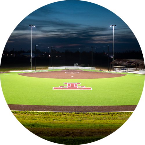 Softball field with red Tuttle High School logo lit by two LED light poles and fixtures.