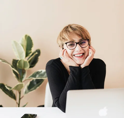 A women with short hair and glasses is smiling into the camera