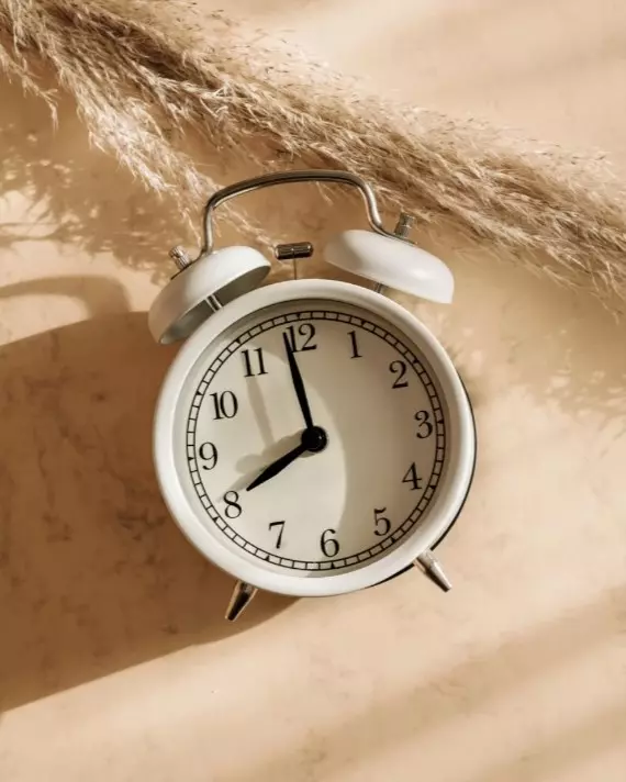 kid holding up a red alarm clock