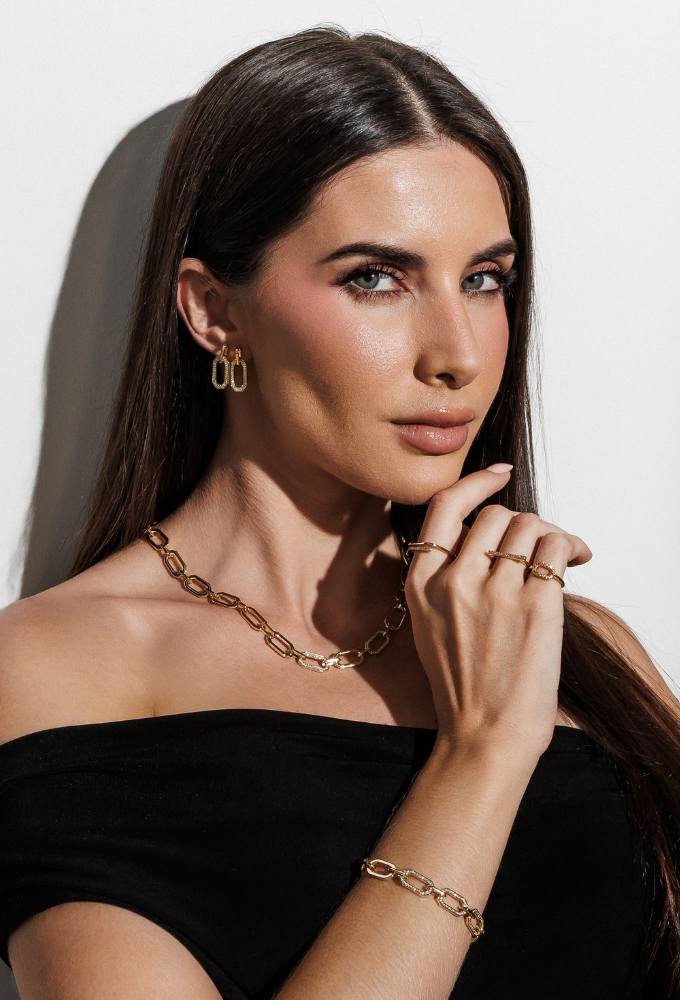 Mulher em pose elegante apresentando semijoias douradas