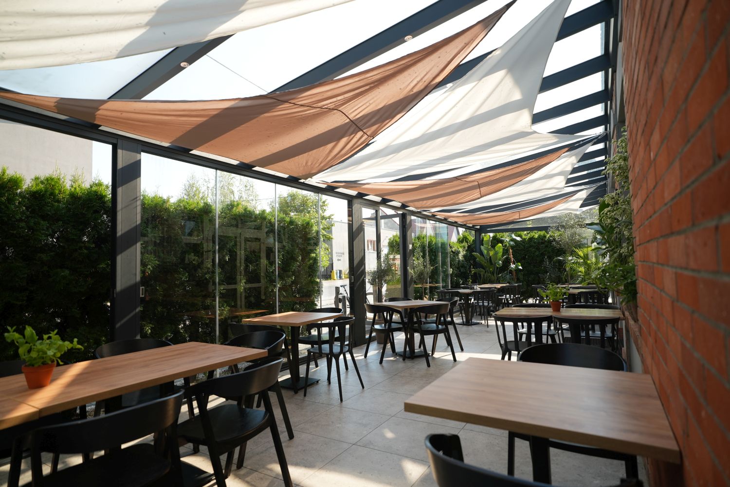 Przeszklona weranda restauracji otoczona zielenią
