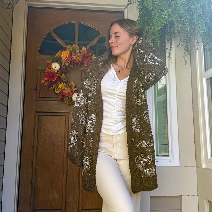 Woman in a gray herringbone blazer, jeans, and black boots.